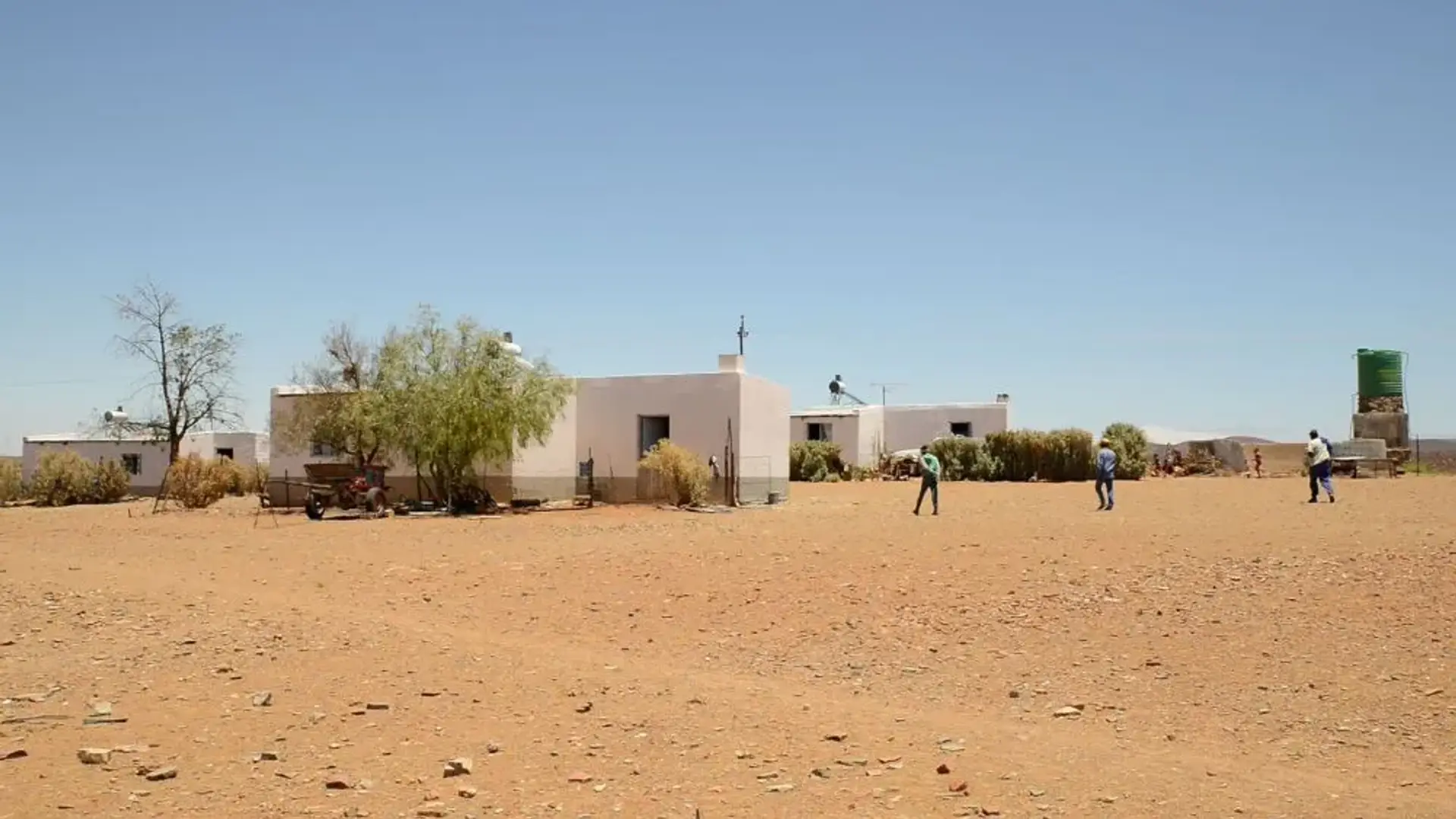 A wideshot of children playing on a desert with their home in the backgound