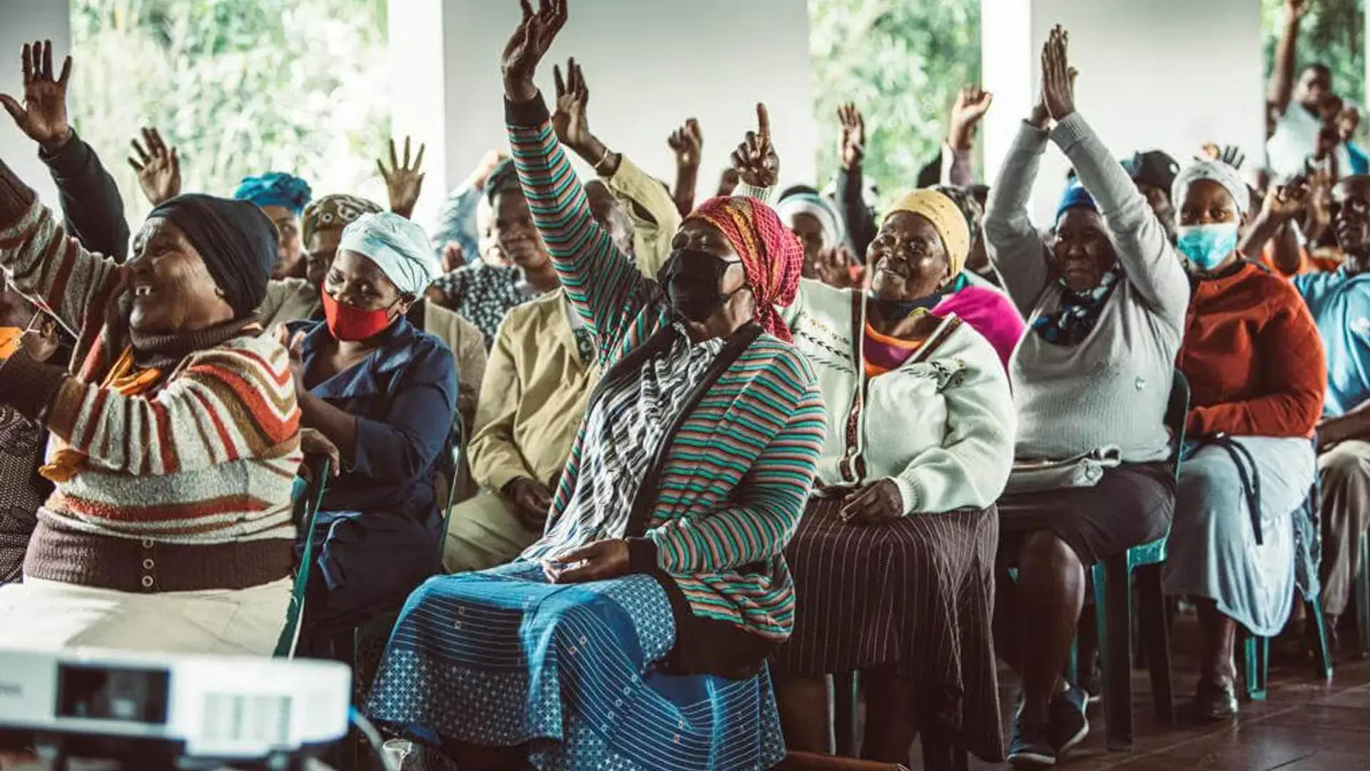 Elderly women raising their hands at a community gathering