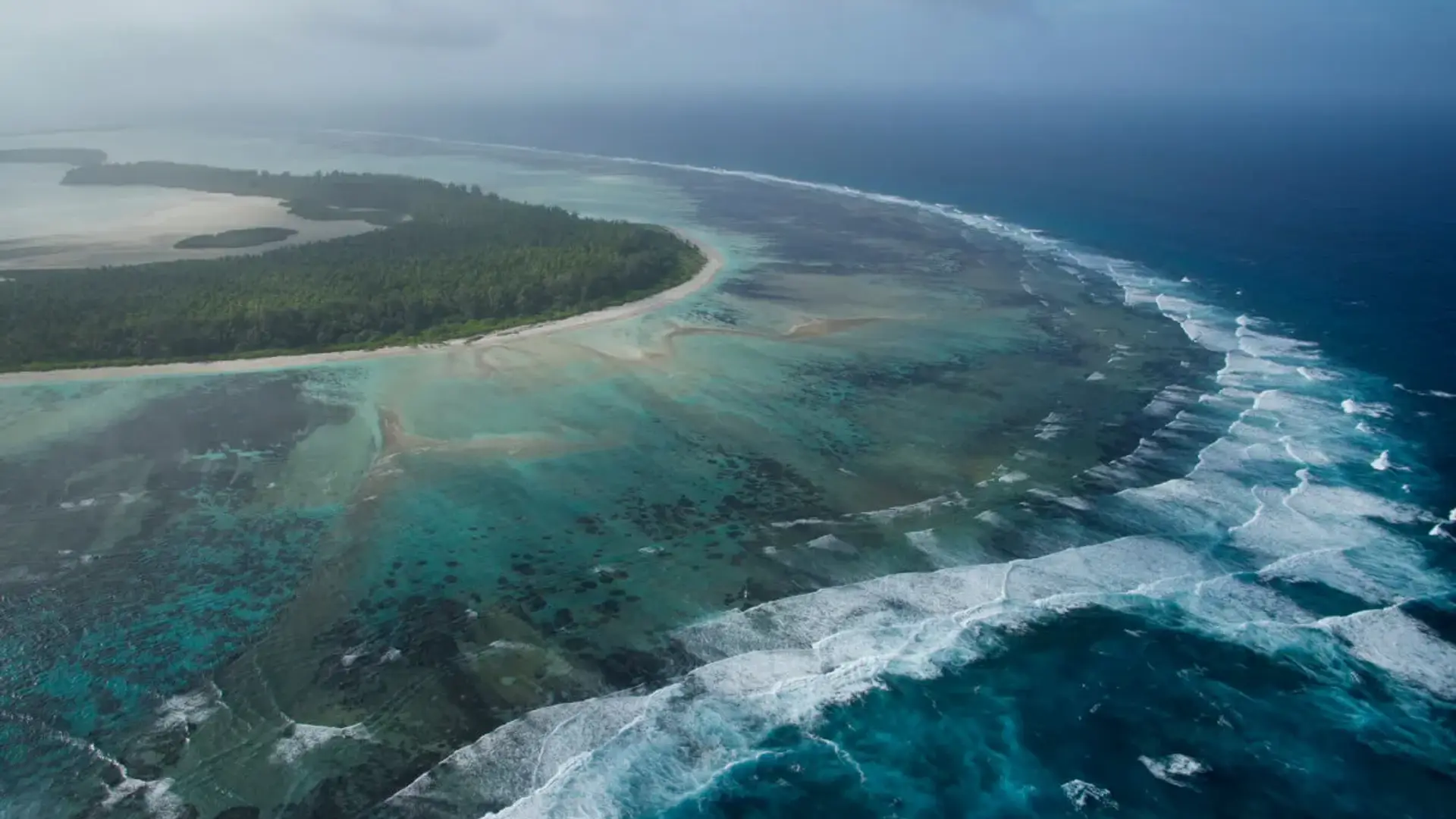 Arial shot of the ocean meeting an island beach