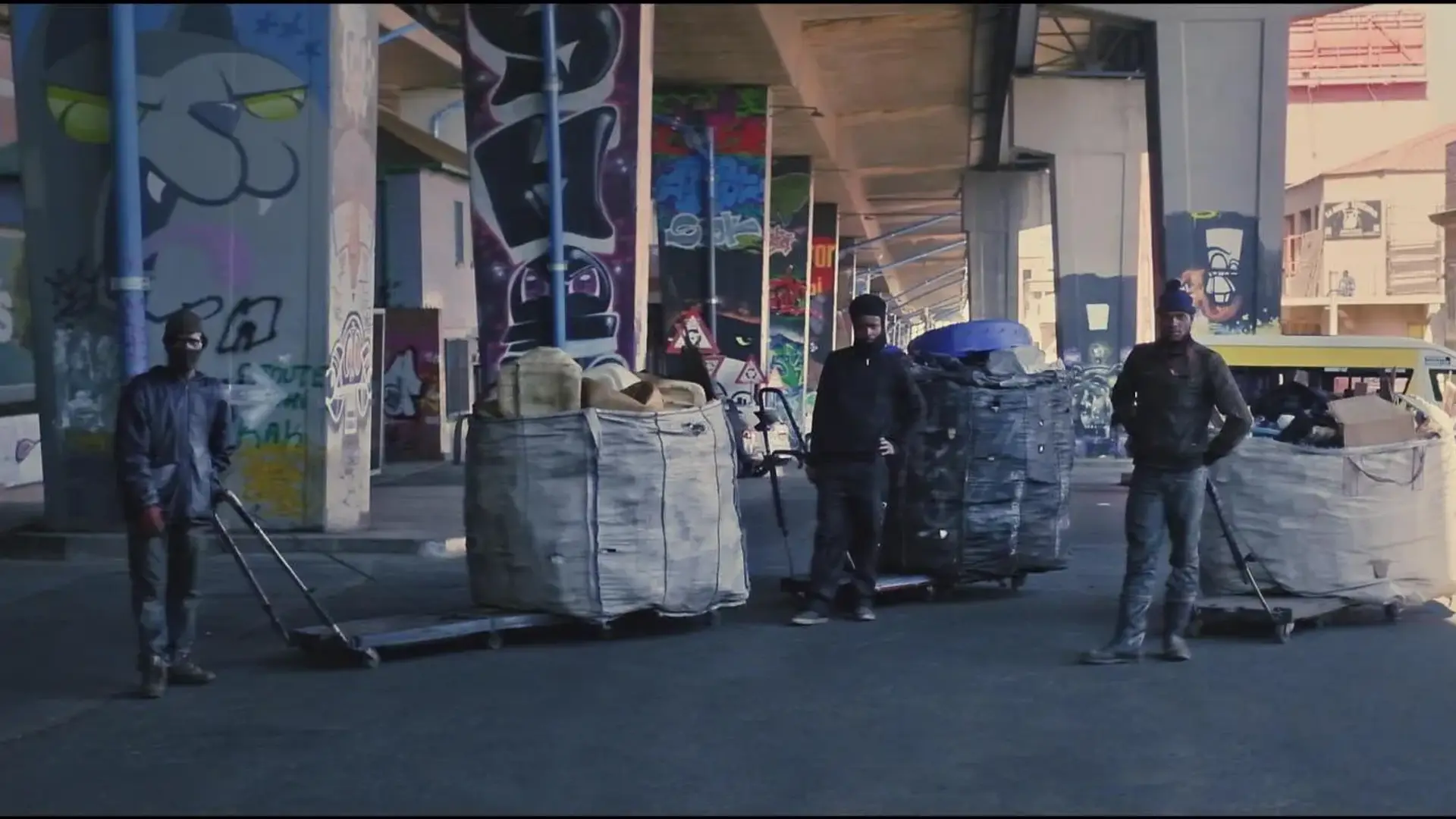 Three men each holding trolleys on which they put huge waste bag