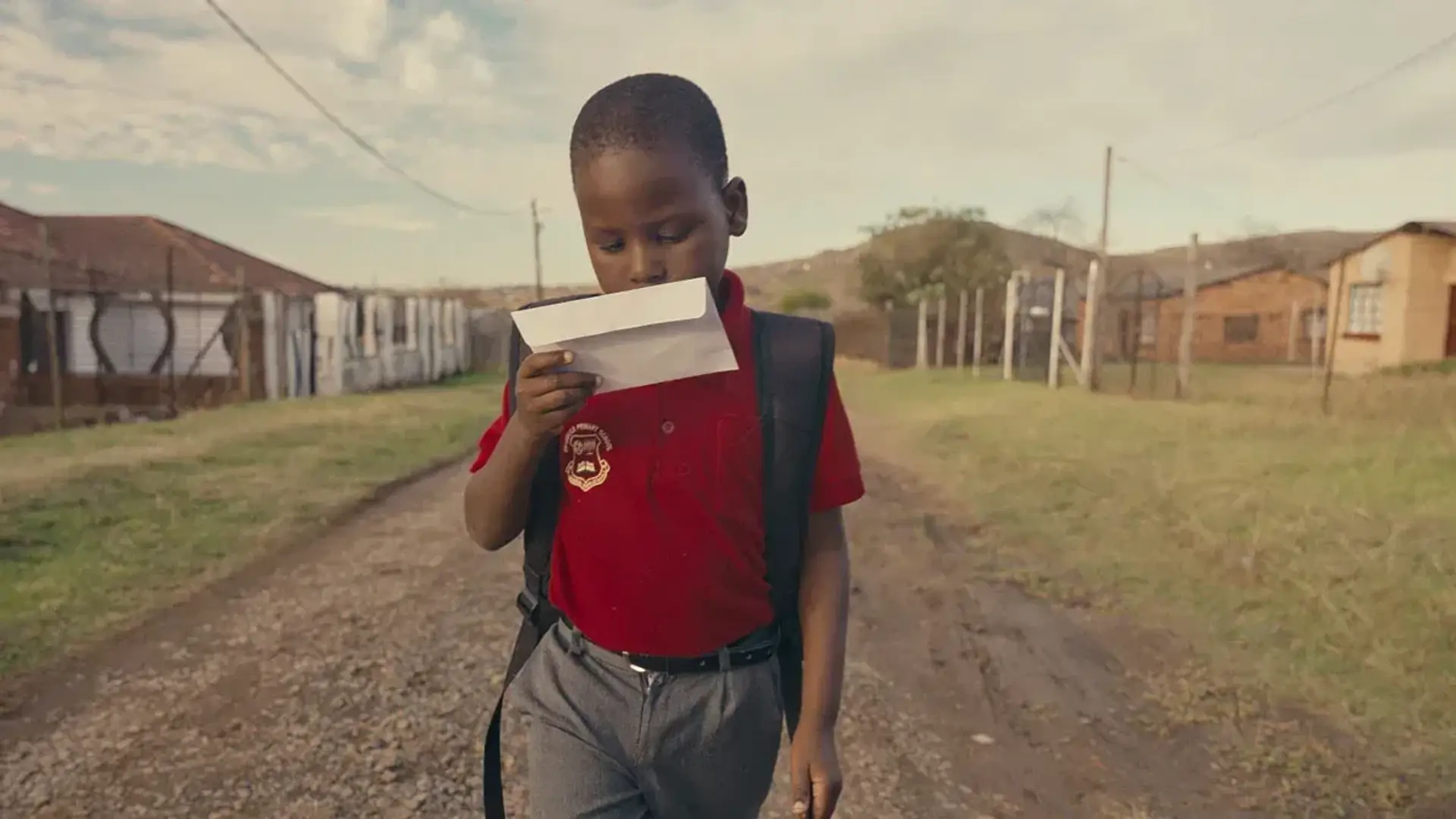 A school boy holding an envelope